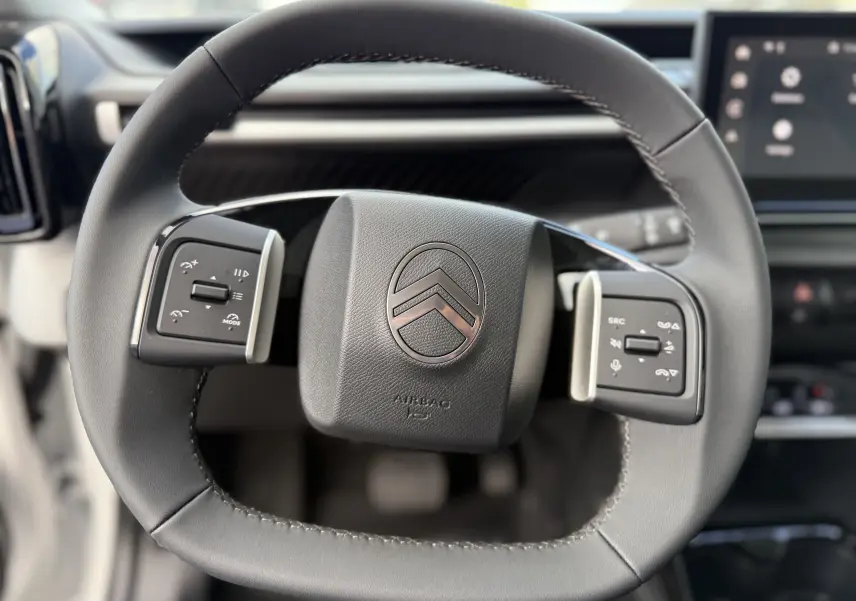 Gros plan sur le volant cuir noir du Citroën C3 Aircross 2026 avec commandes intégrées et logo central chromé.