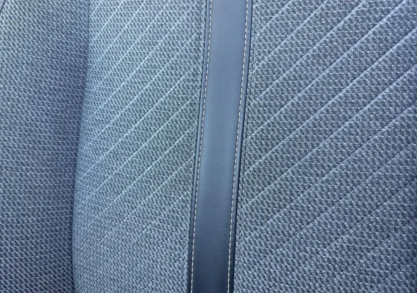 Gros plan sur le tissu gris à motif rayé et la bande centrale en simili cuir du siège avant de la Peugeot 208.