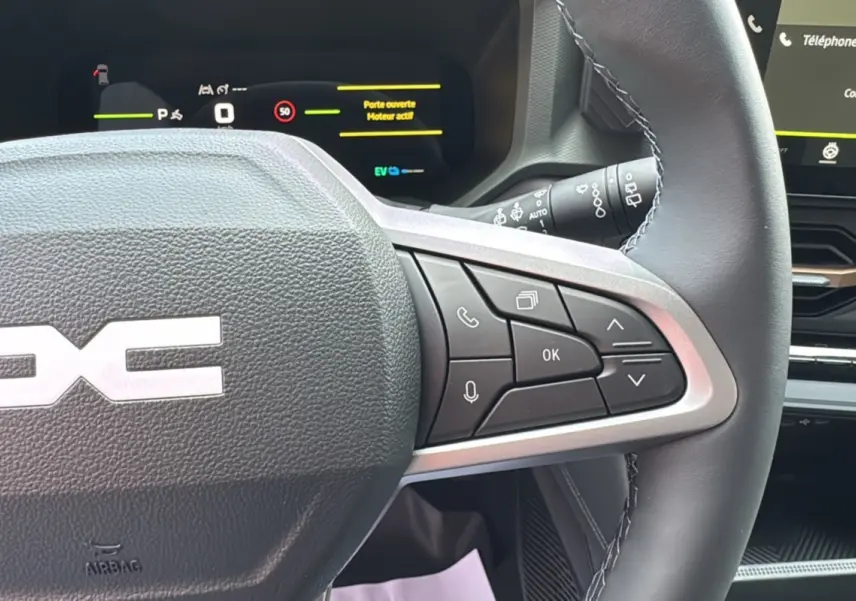 Gros plan sur le volant cuir gris avec commandes multifonctions du tableau de bord digital du Dacia Bigster Hybrid 155 Extreme Plus.