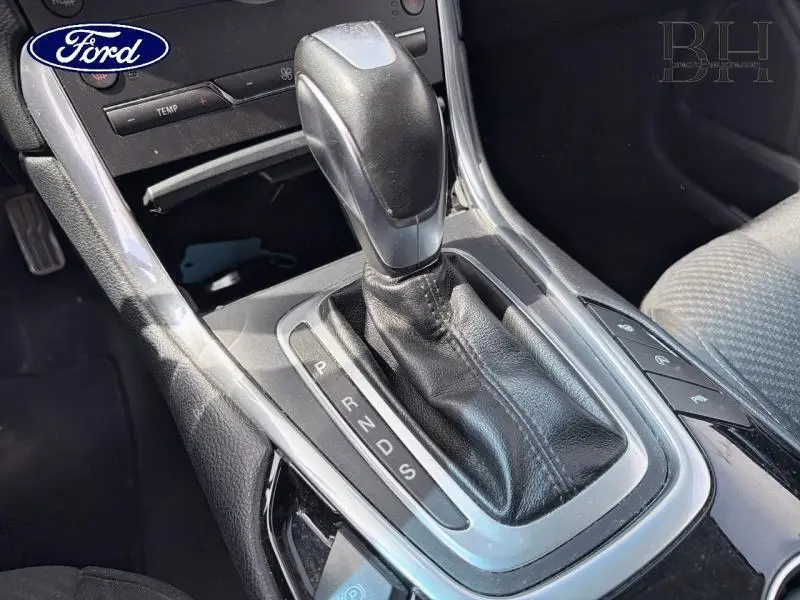 Gros plan sur le levier de vitesses automatique en cuir noir du Ford Edge gris Ingot, avec commandes autour visibles.