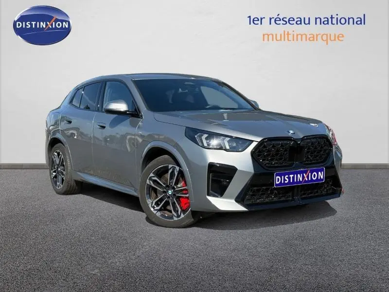 BMW X2 sDrive20dA 2025 gris Skyscraper, vue 3/4 avant avec jantes alu noires et étriers de frein rouges.