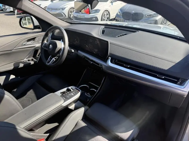 Vue intérieure côté conducteur du BMW X2 2025 en Skyscraper Grey, avec tableau de bord numérique et volant cuir multifonction.