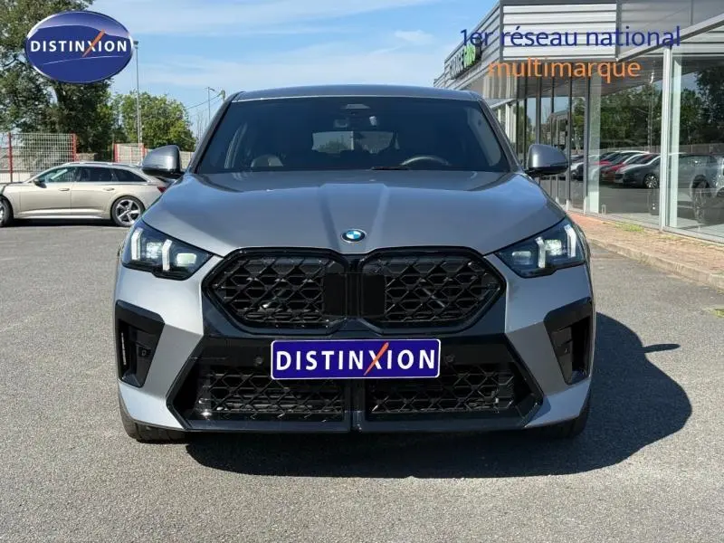 Vue frontale d'un BMW X2 sDrive20dA 2025 en Skyscraper Grey métallisé avec calandre noire et phares LED allumés.