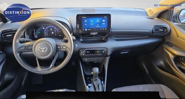 Vue intérieure avant de la Toyota Yaris Hybride 116h Design 2026 gris foncé, tableau de bord avec écran tactile central et volant multifonctions cuir.