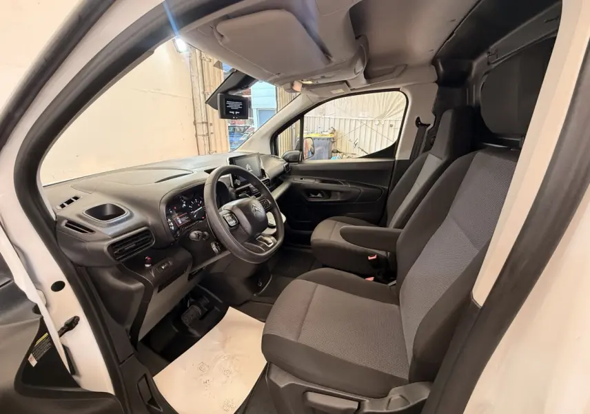 Intérieur côté conducteur du Citroën Berlingo blanc 2022, montrant les sièges et le tableau de bord moderne.