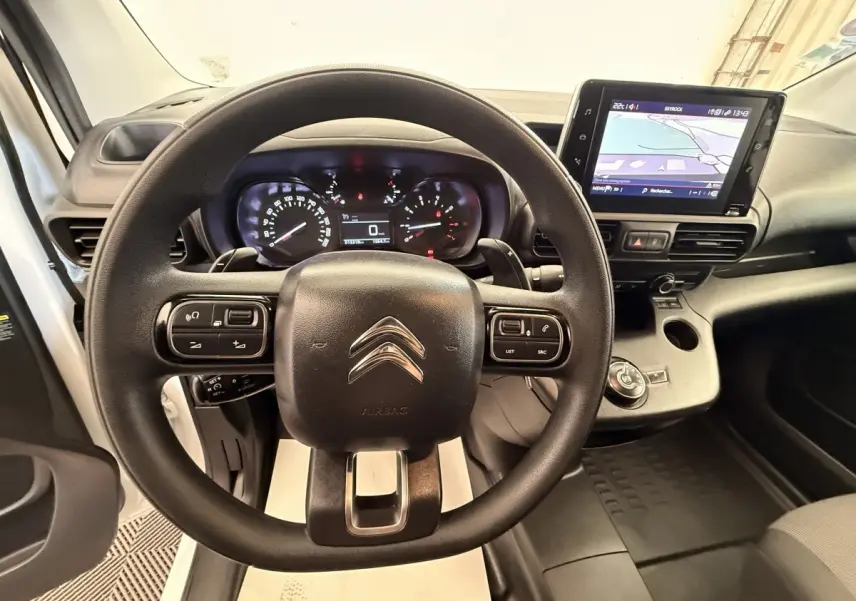 Vue intérieure centrée sur le volant Citroën d'un Berlingo blanc avec écran tactile et tableau de bord numérique.