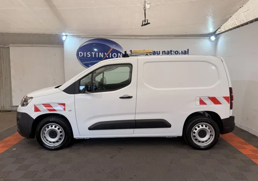 Profil droit d’un utilitaire Citroën Berlingo blanc 2022 avec bandes réfléchissantes rouges et blanches sur ailes avant et arrière.