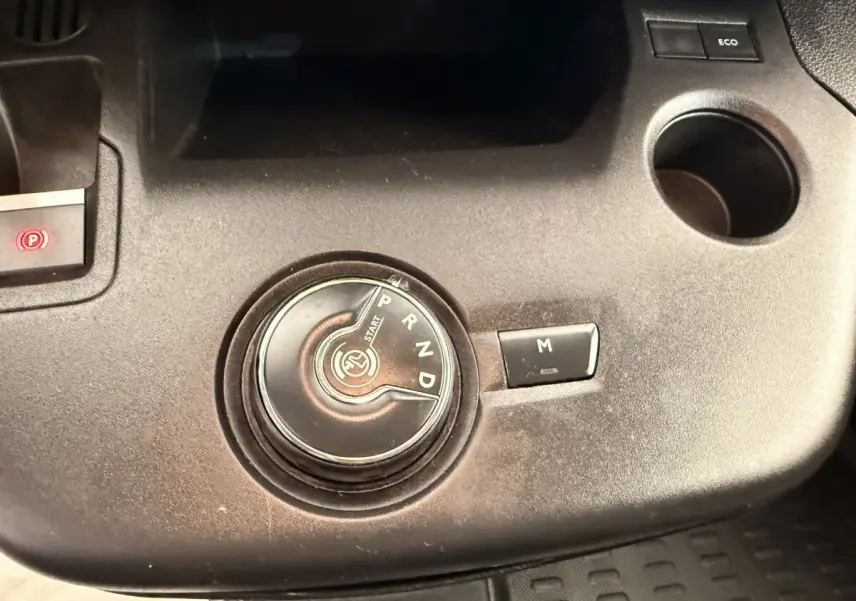 Gros plan sur la commande rotative de la boîte automatique du Citroën Berlingo blanc, avec bouton mode manuel et frein électrique.