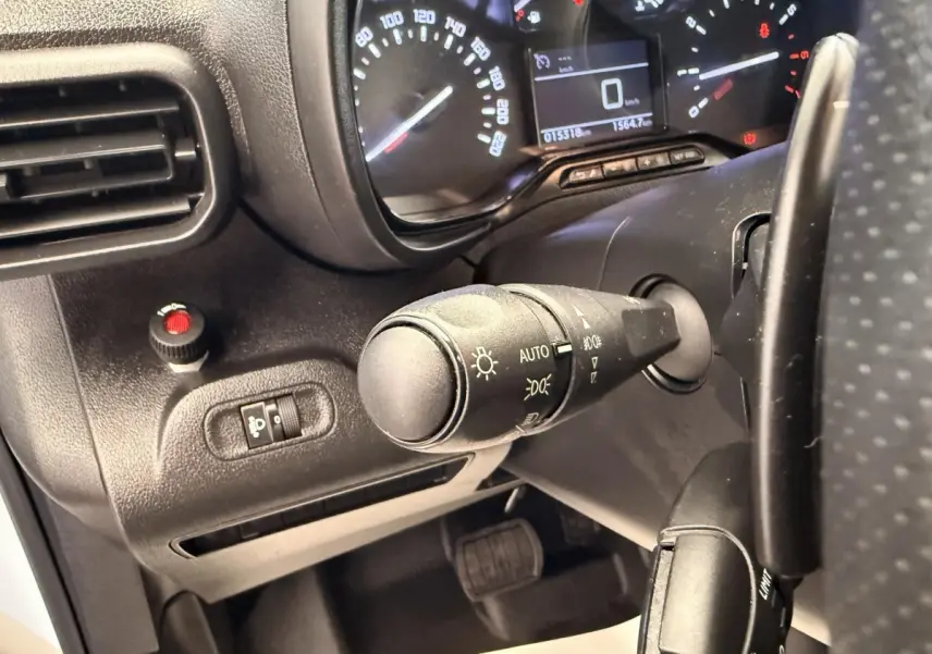 Gros plan sur la commande des phares et le tableau de bord du Citroën Berlingo blanc, vue côté conducteur.