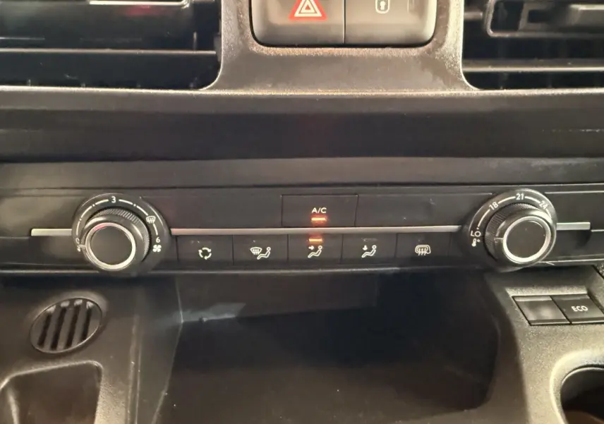 Vue rapprochée du tableau de bord noir du Citroën Berlingo 2022, avec commandes climatisation et bouton A/C allumé.