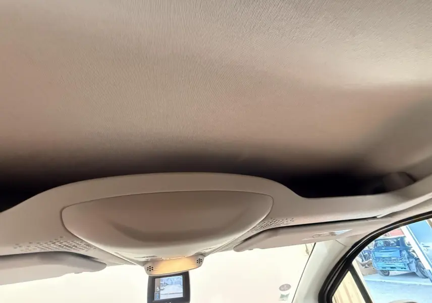 Vue intérieure du plafond avant beige du Citroën Berlingo blanc, avec miroir de surveillance et pare-soleil côté droit visible.