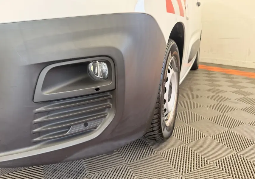 Gros plan sur l'antibrouillard avant droit et la roue acier du Citroën Berlingo blanc, vue de profil avant.