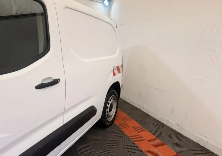 Vue latérale arrière droite d’un utilitaire Citroën Berlingo blanc avec marquage réfléchissant rouge et blanc.
