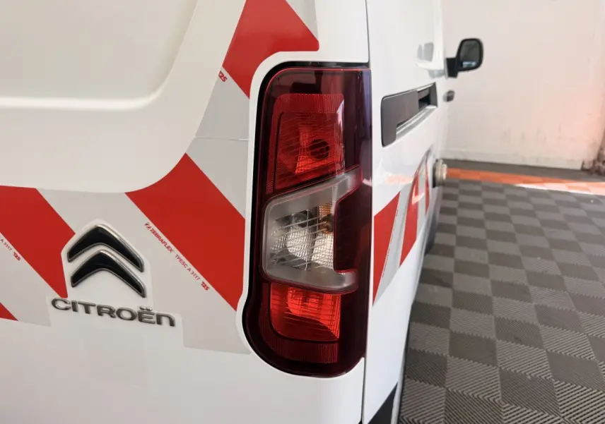 Gros plan sur l’arrière droit blanc du Citroën Berlingo 2022 avec bandes rouges de signalisation et feu arrière.