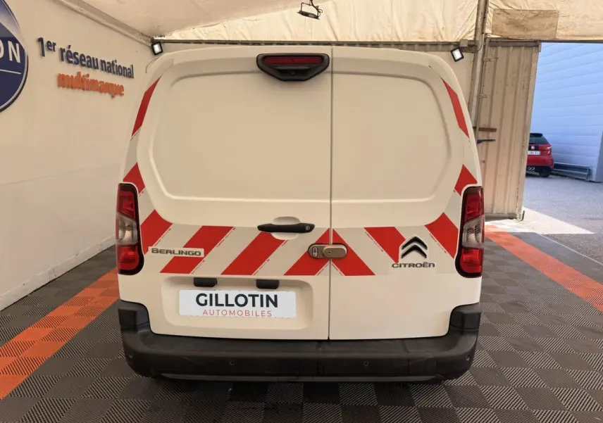 Vue arrière d’un Citroën Berlingo blanc avec bandes rouges réfléchissantes et logo constructeur visible.