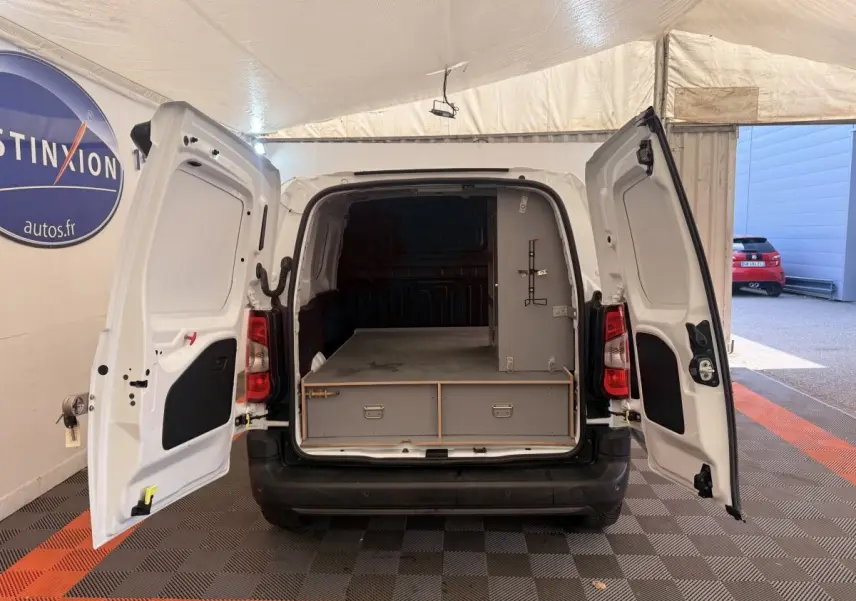 Vue arrière d’un Citroën Berlingo blanc 2022 avec portes ouvertes montrant l’espace de chargement aménagé.