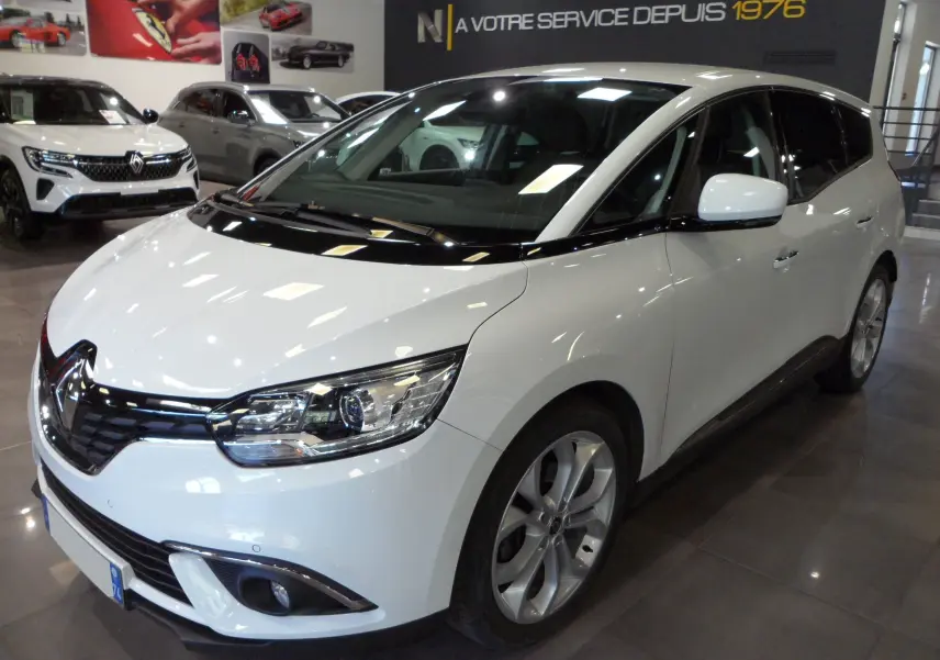 Renault Grand Scenic IV blanc glacier vu en 3/4 avant droit dans un showroom avec jantes alliage visibles.