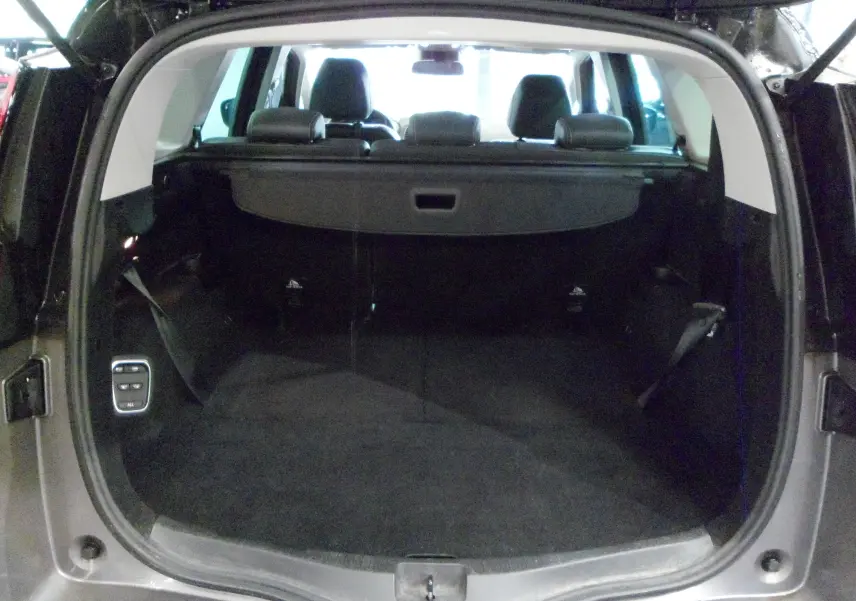 Coffre ouvert vu de l'arrière d'un Renault Grand Scenic IV gris Cassiopé avec intérieur noir et banquettes rabattues.
