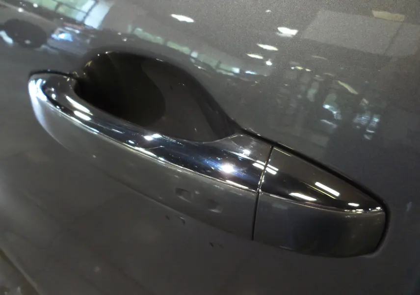 Poignée de porte avant droite chromée sur Renault Grand Scenic IV gris Cassiopé avec reflet intérieur showroom.