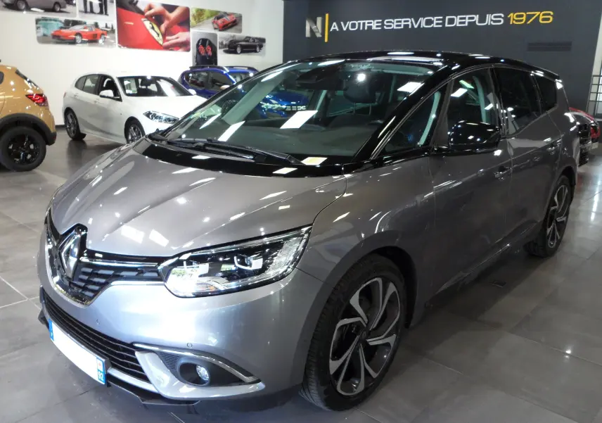 Renault Grand Scenic IV gris Cassiopé avec toit noir, vue 3/4 avant droit en intérieur showroom.