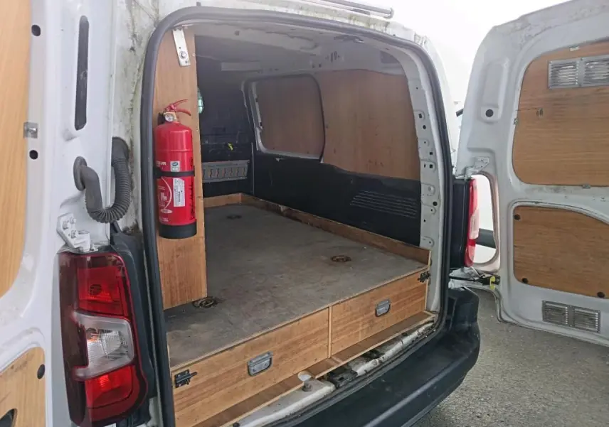 Vue arrière ouverte du Citroën Berlingo blanc 2020, montrant l’aménagement bois intérieur avec extincteur fixé côté gauche.