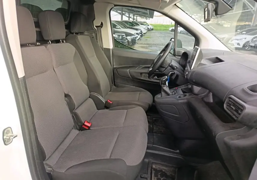 Vue intérieure côté conducteur du Citroën Berlingo blanc 2020, montrant les sièges tissu gris et le tableau de bord noir.