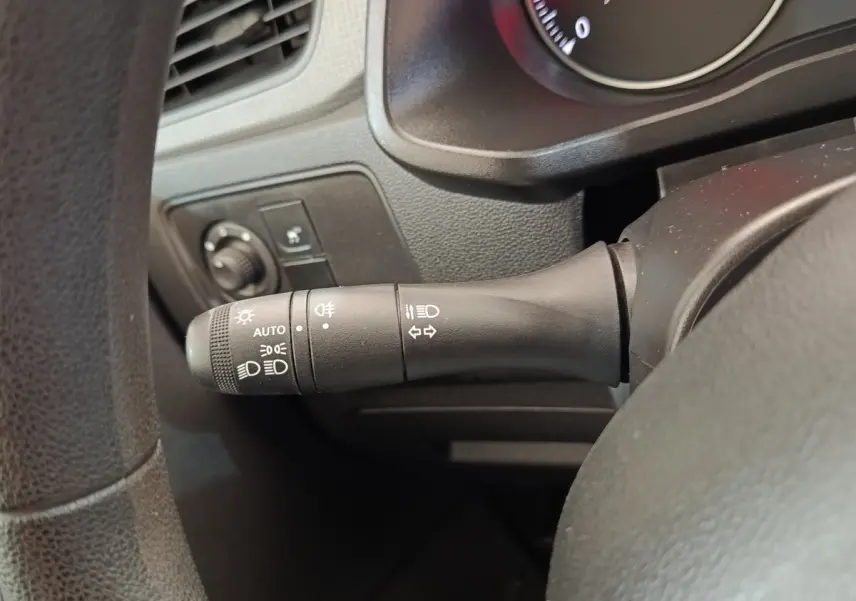 Gros plan sur la commande des phares et clignotants à gauche du volant dans l’habitacle noir du Renault Express blanc.