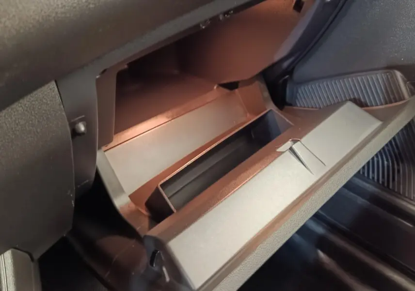 Gros plan sur la boîte à gants ouverte de la Renault Express Confort blanche, intérieur noir mat.