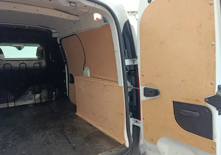 Vue intérieure arrière du Renault Express blanc 2023 avec cloison pleine et revêtement bois des parois de chargement.