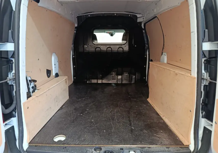Vue intérieure arrière du Renault Express blanc 2023, montrant l'espace de chargement avec cloison pleine vitrée et revêtement bois.