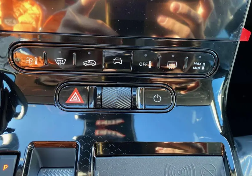 Gros plan sur la console centrale noire brillante du Citroën C5 Aircross hybride, avec commandes climatisation et bouton hazard.