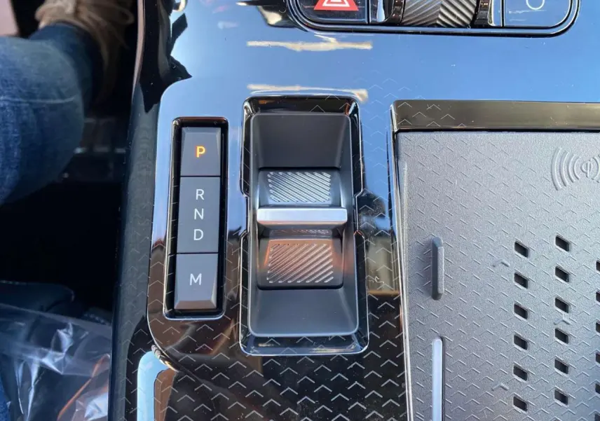 Gros plan sur la console centrale noire brillante du Citroën C5 Aircross avec sélecteur de vitesses électronique et zone de recharge sans fil.
