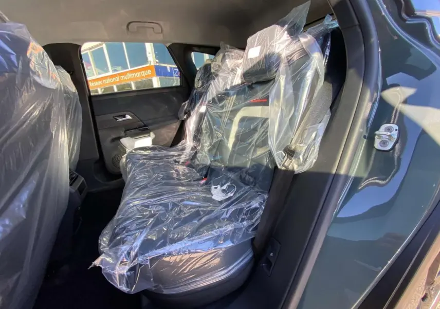 Vue intérieure côté droit des sièges arrière protégés par des housses plastiques sur un Citroën C5 Aircross vert.