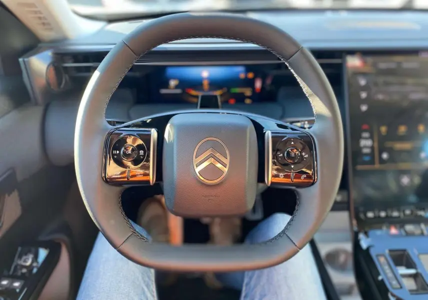 Vue intérieure centrée sur le volant du Citroën C5 Aircross 2026, avec commandes intégrées et tableau de bord numérique flou.