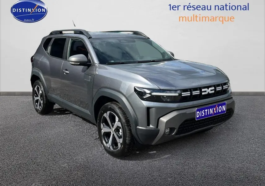 SUV Dacia Duster gris schiste en 3/4 avant droit avec jantes alu et barres de toit visibles.
