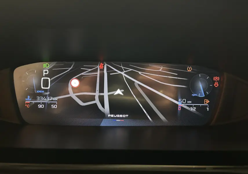 Tableau de bord numérique de Peugeot 308 rouge 2024, affichant la navigation GPS et les indicateurs de vitesse et carburant.