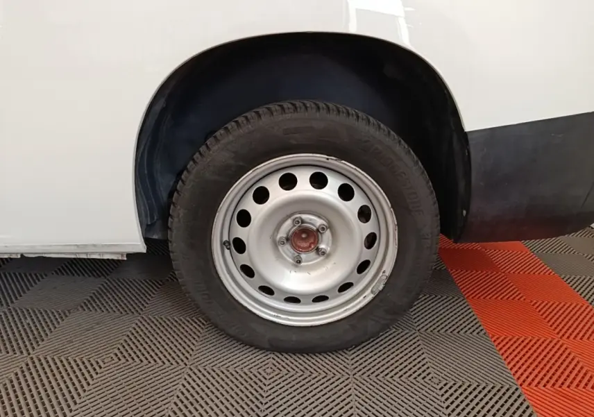 Gros plan sur la roue arrière droite en jante acier du Citroën Berlingo XL blanc, partie basse de la carrosserie visible.