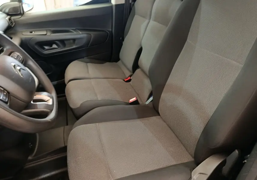 Vue intérieure côté conducteur du Citroën Berlingo 2020, sièges tissu gris et volant multifonctions noir.