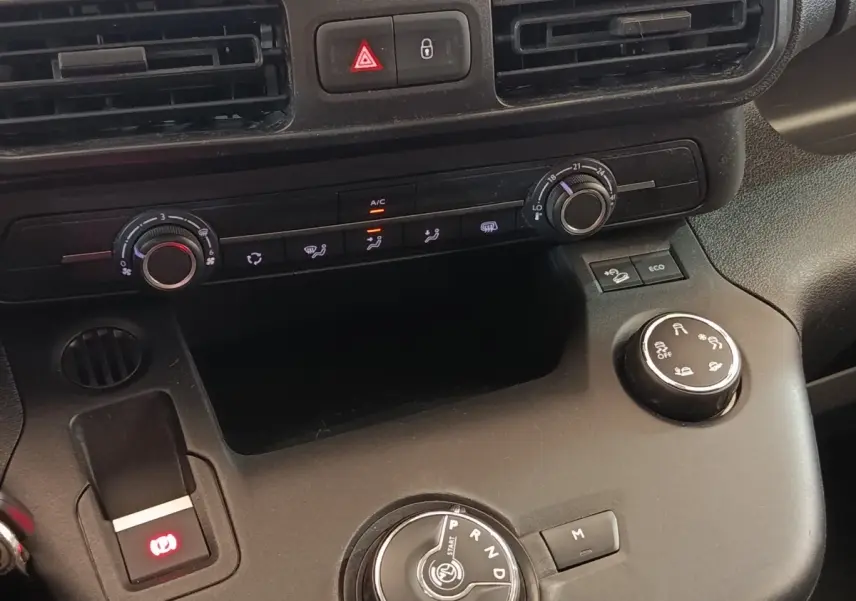 Vue rapprochée du tableau de bord et console centrale noire du Citroën Berlingo blanc, avec commandes climatisation et boîte auto.