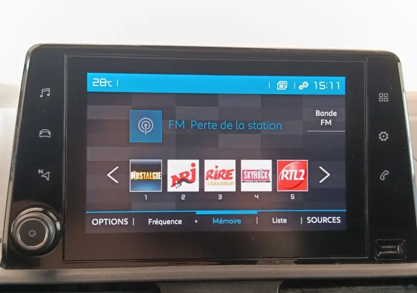 Écran tactile central du tableau de bord du Citroën Berlingo blanc, affichant les stations radio FM.
