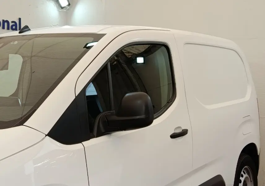 Vue de profil côté gauche d’un utilitaire Citroën Berlingo blanc avec porte latérale pleine et rétroviseur noir.