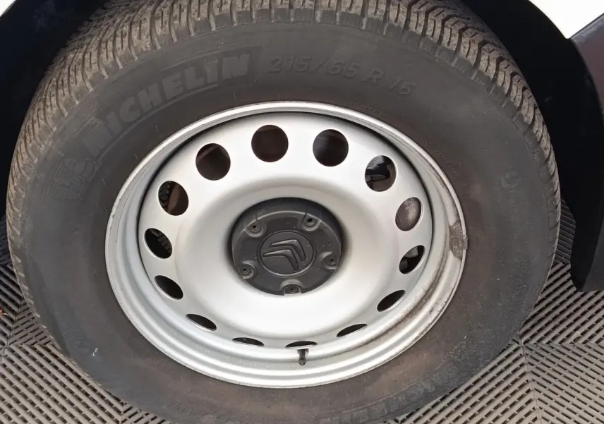 Gros plan sur la roue acier blanche avec logo Citroën, pneu Michelin, sur un Citroën Berlingo blanc.