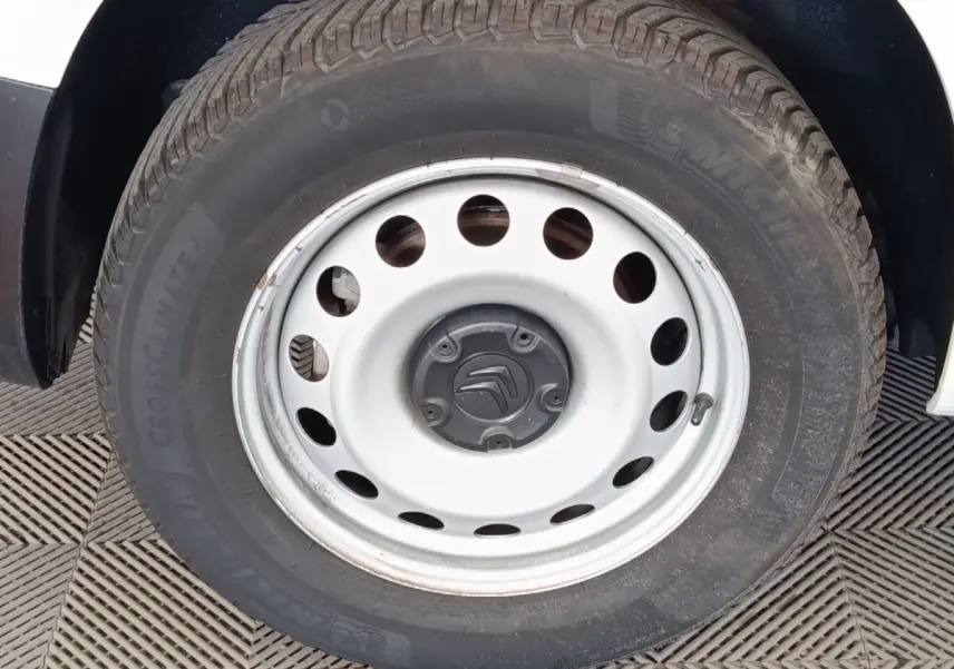 Gros plan sur la roue acier blanche du Citroën Berlingo blanc, montrant le pneu Michelin et le logo Citroën central.