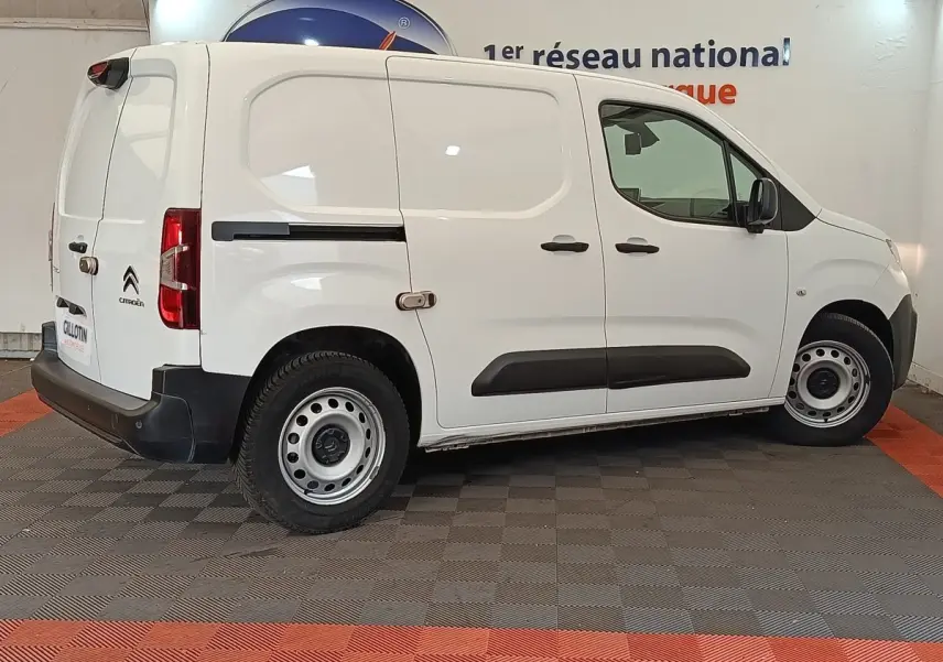 Vue de profil droit d’un utilitaire Citroën Berlingo blanc avec jantes acier et protections latérales noires.
