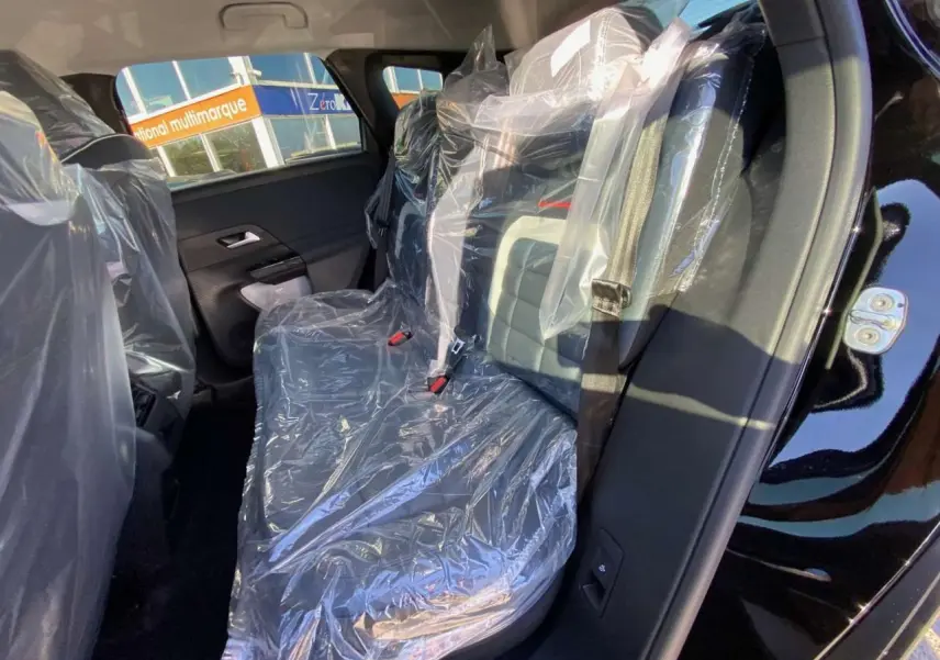 Vue intérieure côté gauche des sièges arrière protégés par des housses plastiques d'un Citroën C5 Aircross noir.