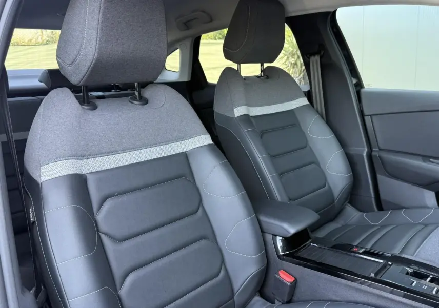 Vue rapprochée des sièges avant bi-matière gris et noir du Citroën C4 X 2024, avec accoudoir central.