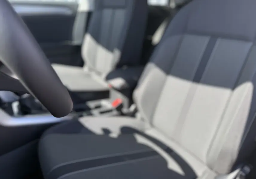 Gros plan sur les sièges avant gris clair du Volkswagen T-Roc 1.5 TSI 150 DSG7, intérieur lumineux et moderne.