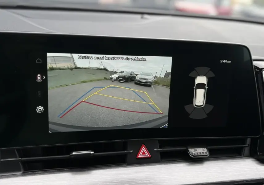 Écran tactile 12" montrant la caméra de recul du Kia Sportage gris perle avec lignes de guidage colorées.