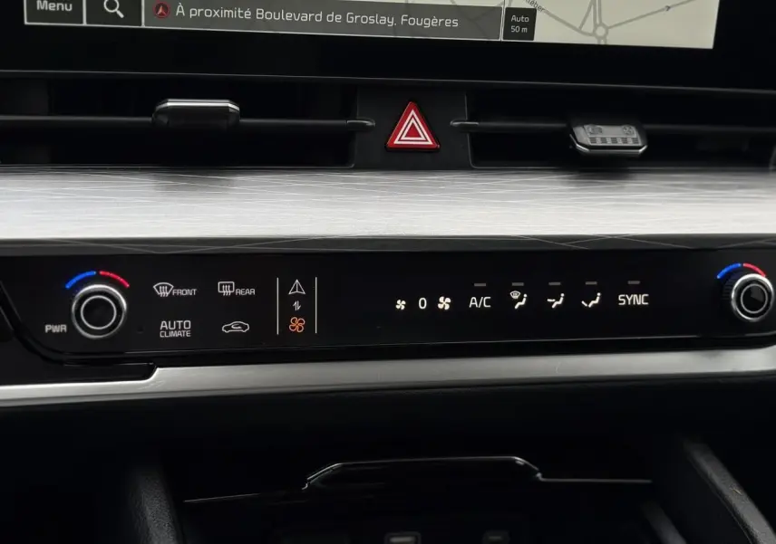 Plan rapproché du tableau de bord noir et gris du KIA SPORTAGE 2025 montrant l'écran tactile 12" et les commandes de climatisation digitales.