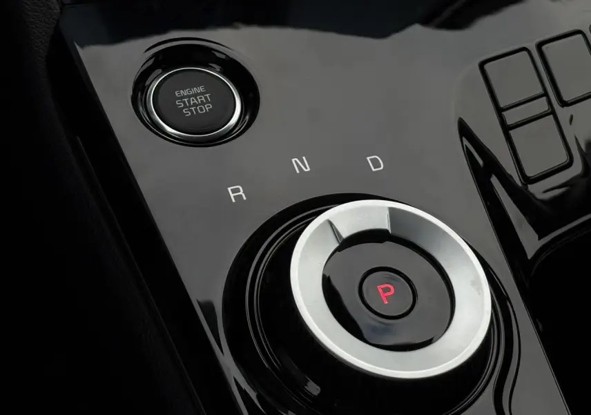 Gros plan sur la molette de sélection de la boîte auto et bouton start/stop du Kia Sportage gris perle.